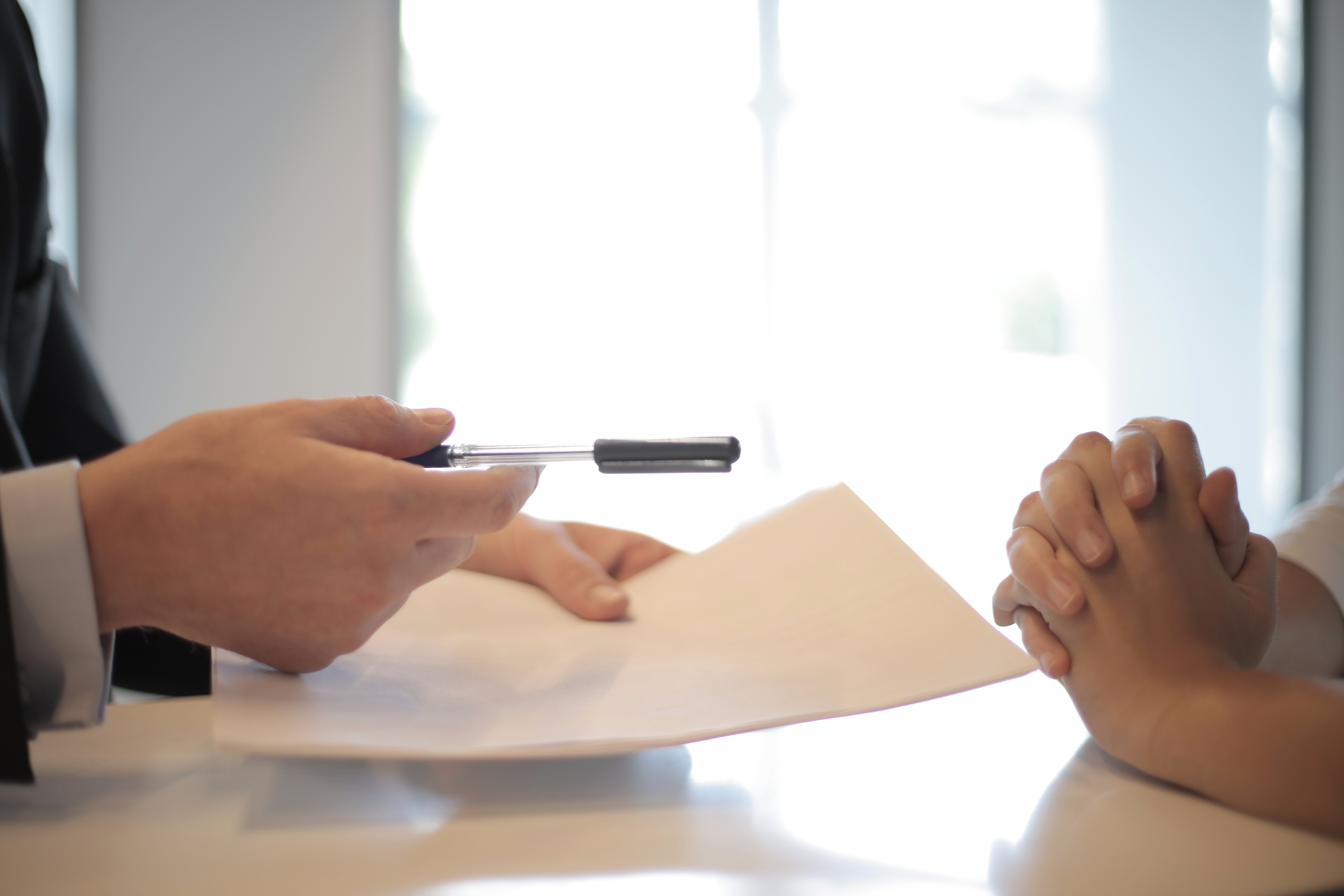 Shows a person being asked to sign documents required for a business bank loan.