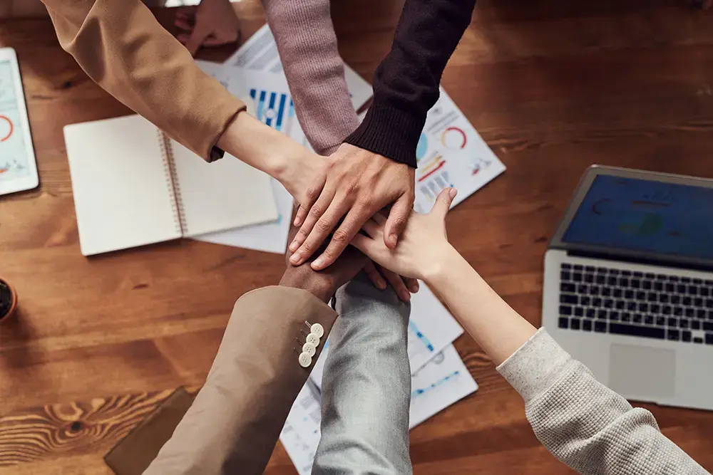 Shows business owners agreeing to a partnership, piling their hands in a team hand-stack.