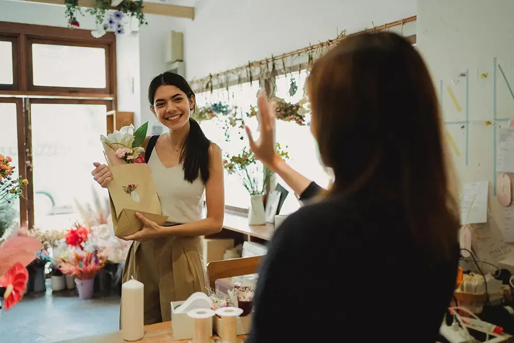 Shows a woman happily buying a bouquet, highlighting high customer lifetime value from positive interactions and repeat purchases.