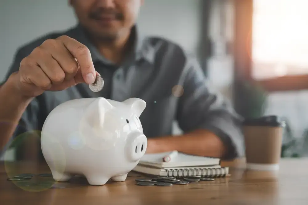 Someone placing a coin in a piggy bank, managing their eCommerce cash flow following best practices and tips.