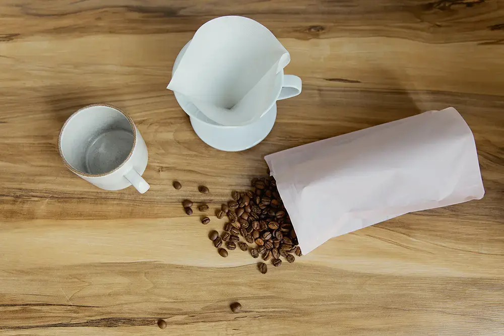 Shows a package of coffee beans on a table, and how the pouch may be reused by customers to store other items afterwards.