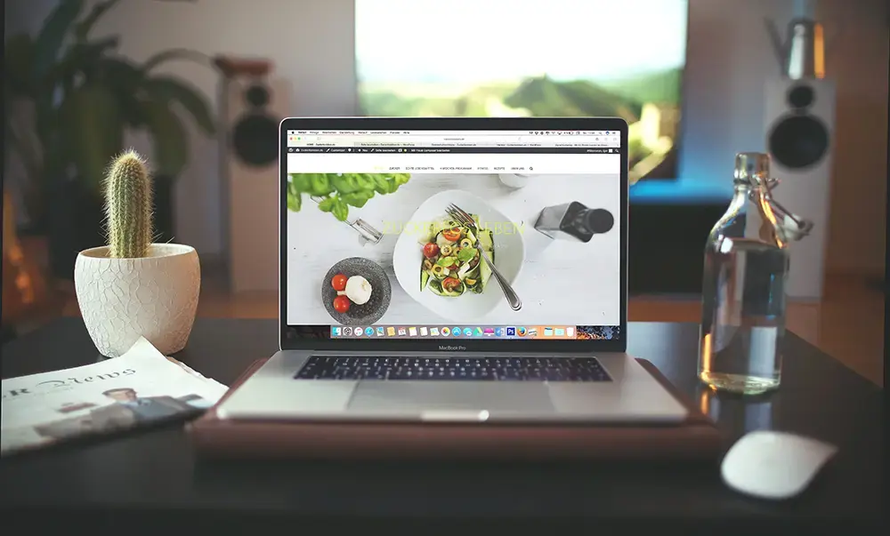 Shows a worktable and an open laptop with an online store's website on display.