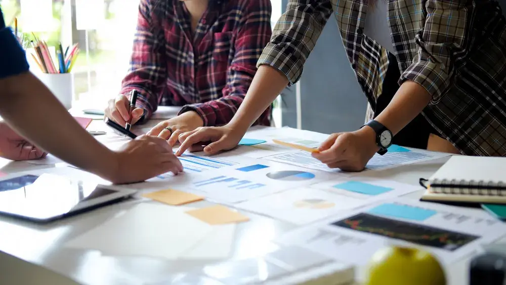 Three people collaborate over a table, planning the details of their promotional giveaway campaign.