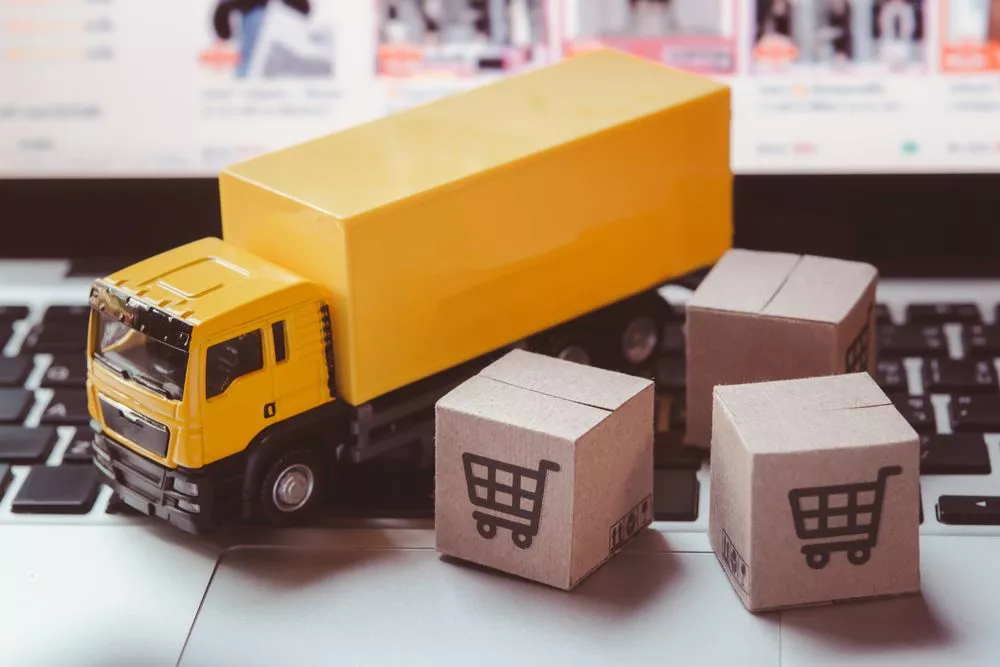 A toy truck, boxes, and a laptop symbolize inventory management software use.