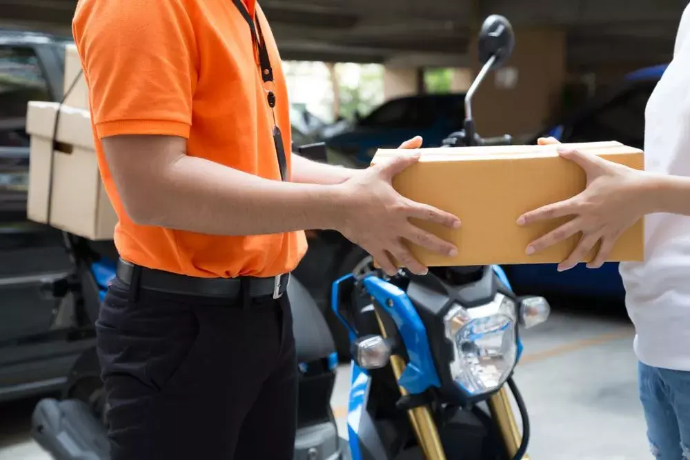 A delivery man hands a package to a customer, completing last-mile delivery for an eCommerce business.