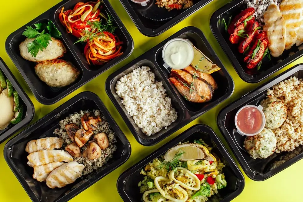 Shows a flat lay of a meal prep business' preparation station and various packaged meals - a good business idea!