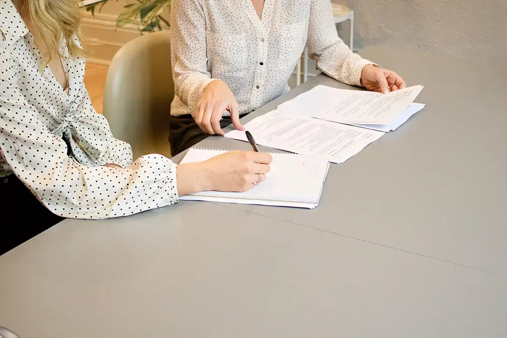 Two seated people reviewing a business' legal requirements, such as certificates and permits.