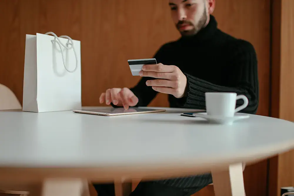 Shows someone at a cafe with a credit card, ready to use it for online purchases from eCommerce sites.