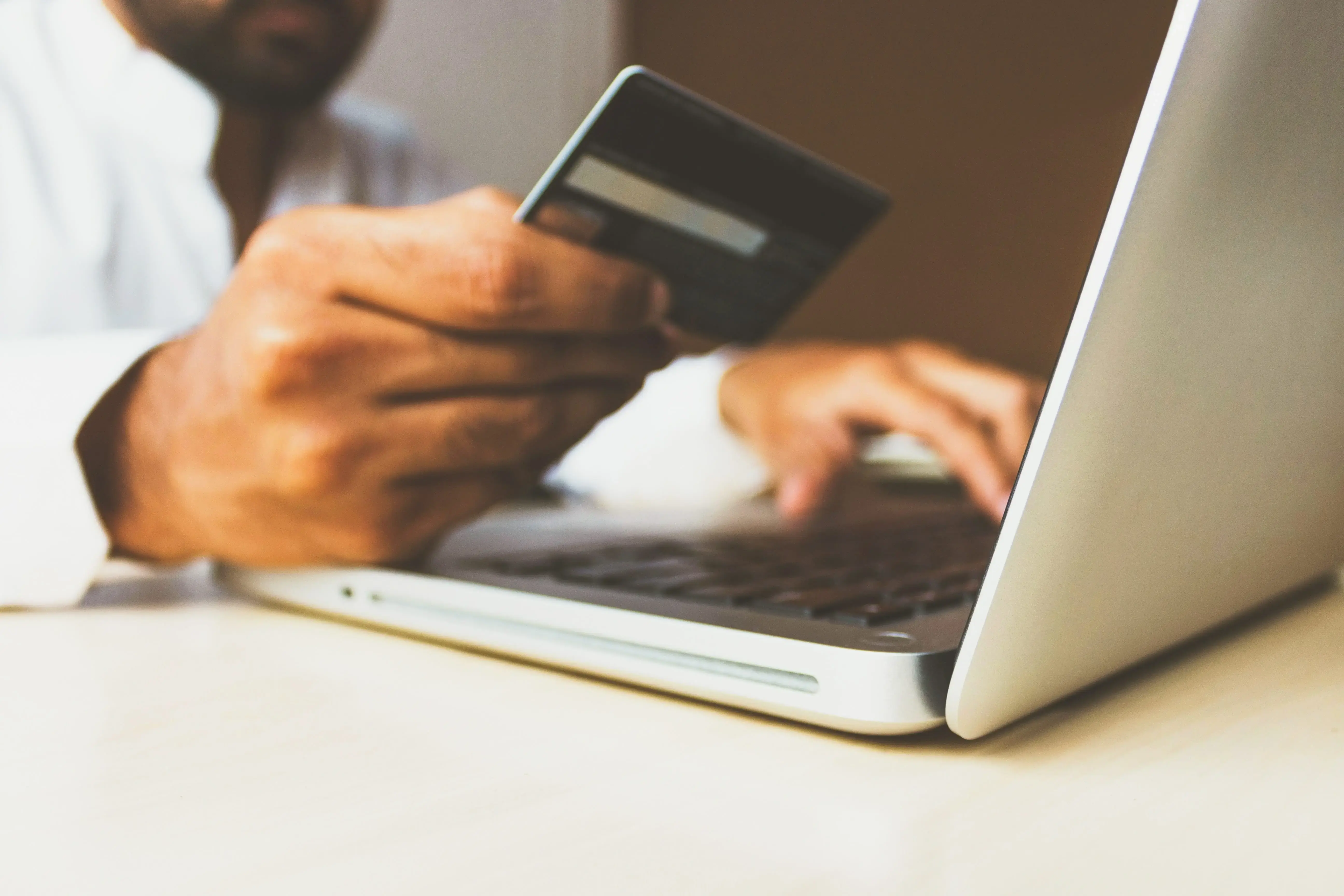 Shows someone using their laptop while holding a credit card, trying to pay for an online purchase.