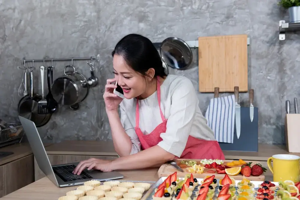 A business owner starts promoting their food business online by setting up digital materials on their laptop.