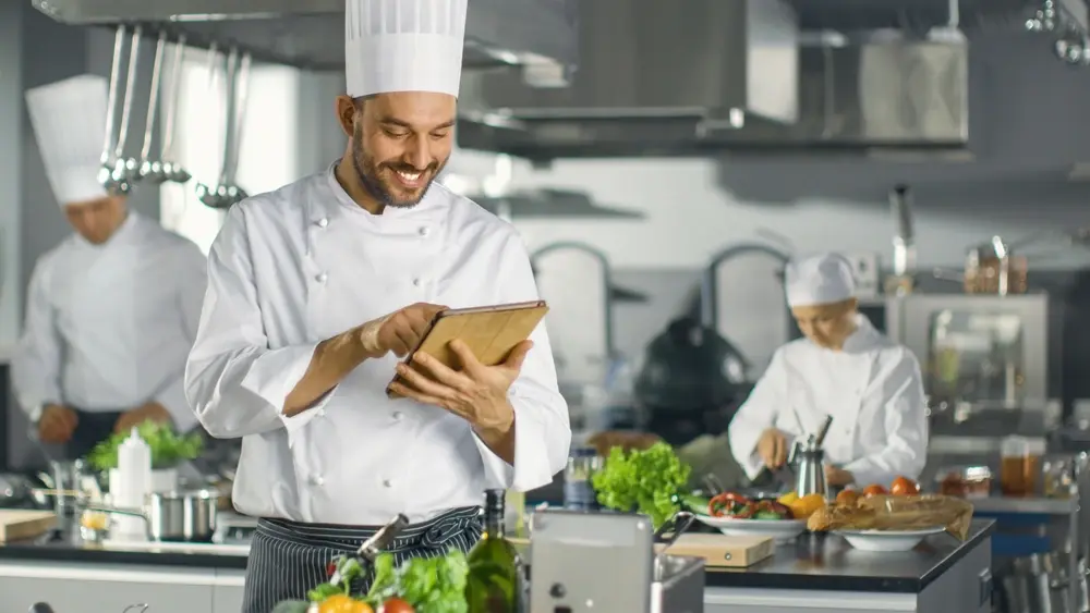 A chef in a kitchen, managing his cloud kitchen business successfully using an eCommerce platform.