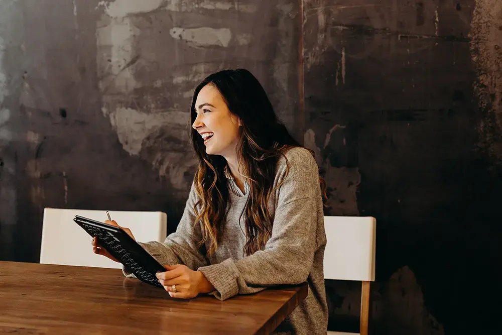 Shows a woman smiling at her phone as she reads a guide about fostering customer loyalty.