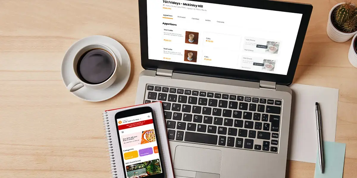 Shows a desk with a laptop and mobile phone featuring eCommerce platforms of a food business.