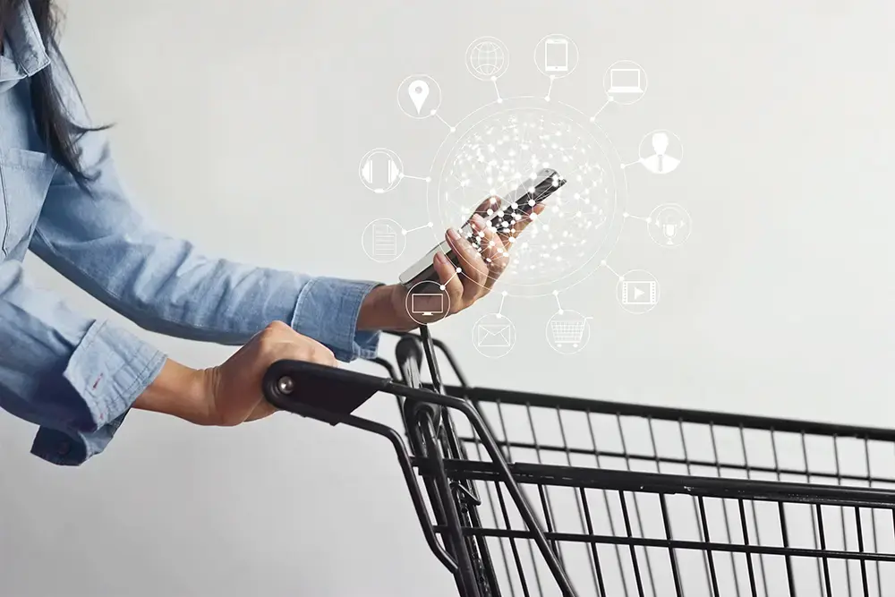 Shows a person browsing a brand's loyalty platforms on their phone while pushing a shopping cart.