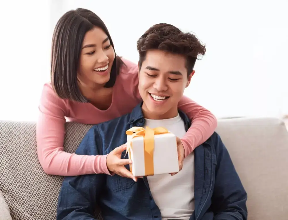 Shows a woman giving a man a gift she bought after seeing a Valentine's Day marketing campaign.