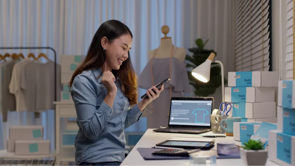 Shows a woman seated at her desk, successfully running her eCommerce business.